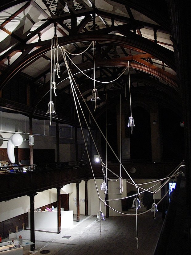 Emma Woffenden: Denied pleasure. No Horizon, part 1, 2003. Exhibition view, a timed mechanical trapeze, a network of glass bells and a fiber glass object 'Spinner'.